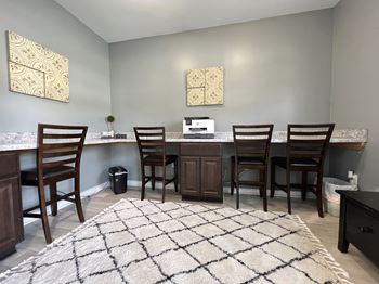 A room with a table surrounded by chairs and two wall hangings.